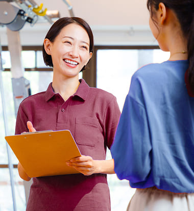 女性のトレーナーが笑顔でお客様とお話ししている写真