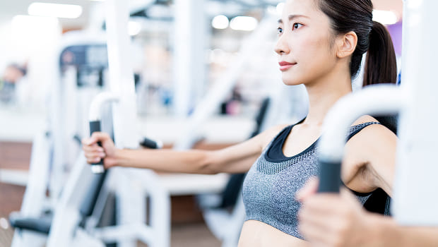 ジムのトレーニングマシンを使っている女性の写真